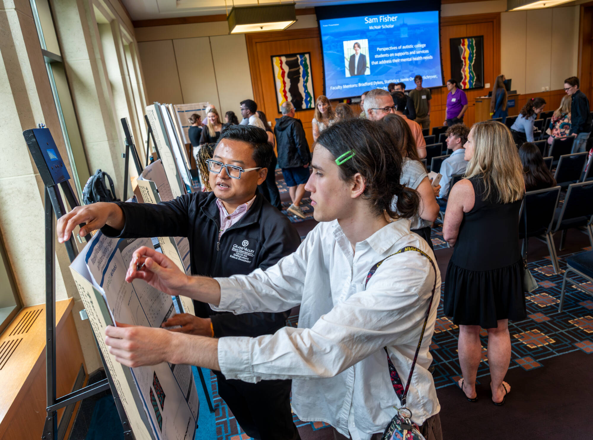 CSRSE assistant Minh Tran, left, helps chemistry major Lucian Forestieri set up his project board as part of the Summer Scholars Showcase on July 25.